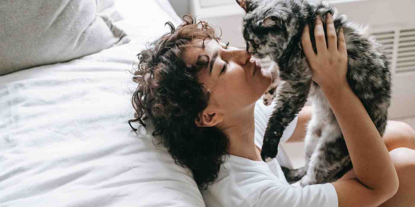photo of a cat owner cuddling and kissing her cat